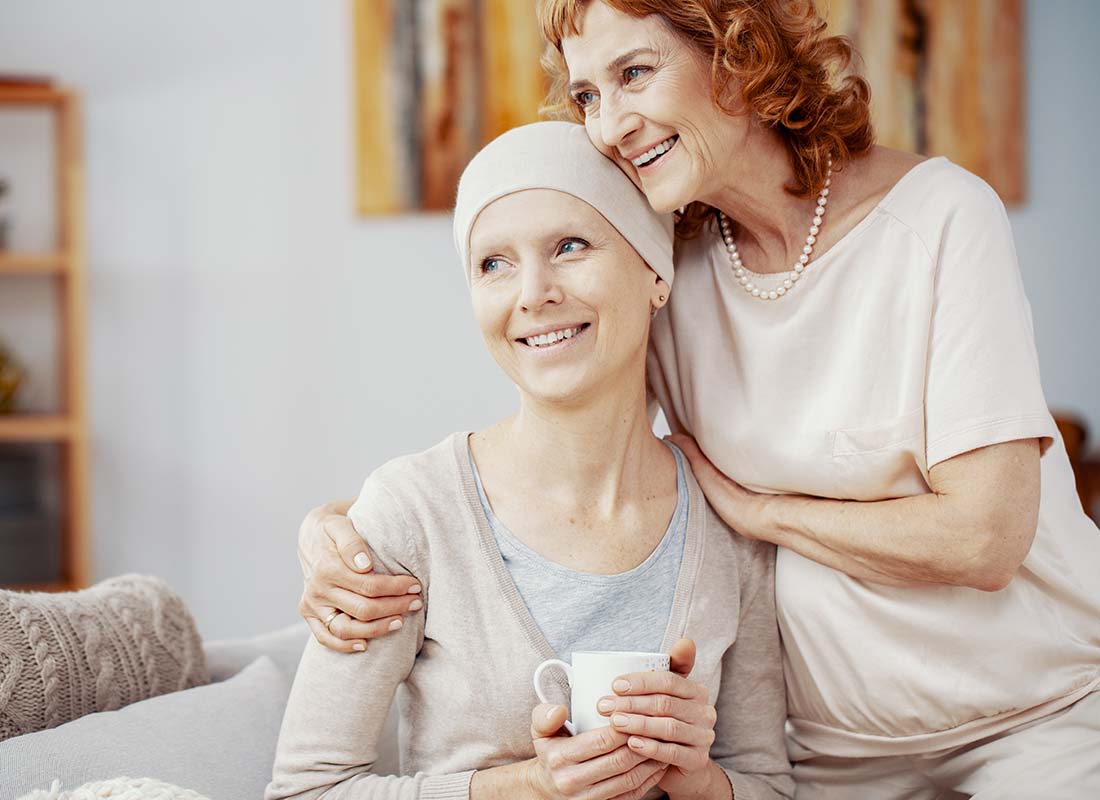 Critical Illness Insurance - Two Woman Staying Positive and Sitting Together at Home Enjoying Their Time Together after a Successful Radiation Therapy Session