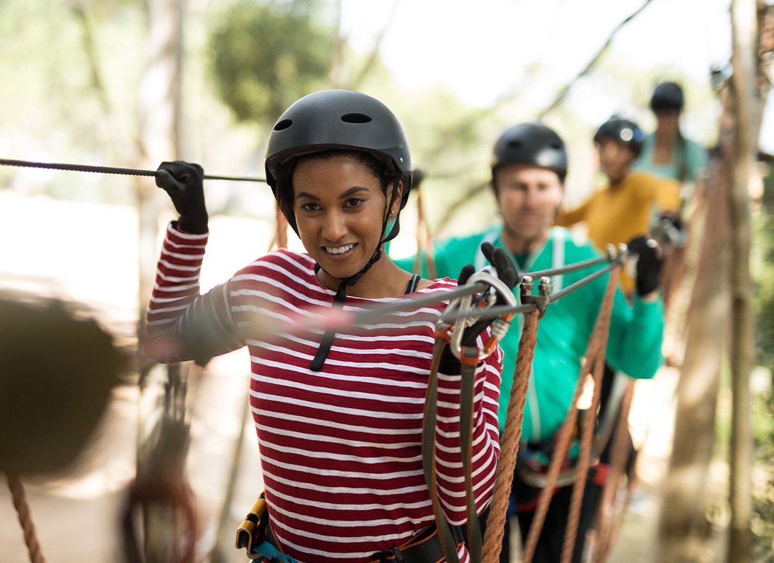 Adventure and Entertainment Insurance - Friends Wearing Helmets and Protective Great While Enjoying a Zip Line in an Adventure in Park